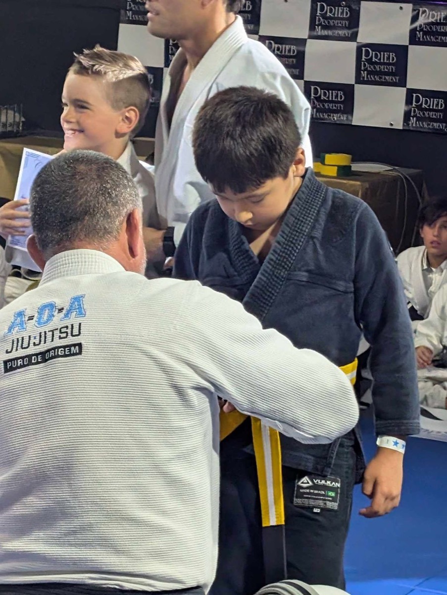 An instructor tying a student's new belt at a studio
